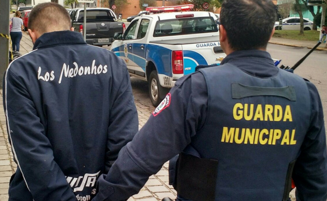 Guarda em pé com o preso também em pé