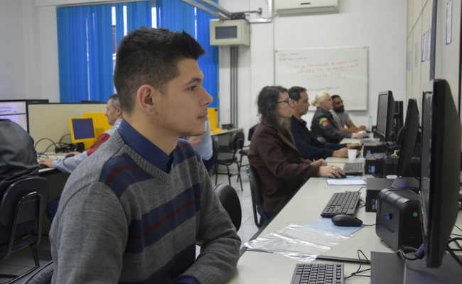 Homem sentando em frente a um computador