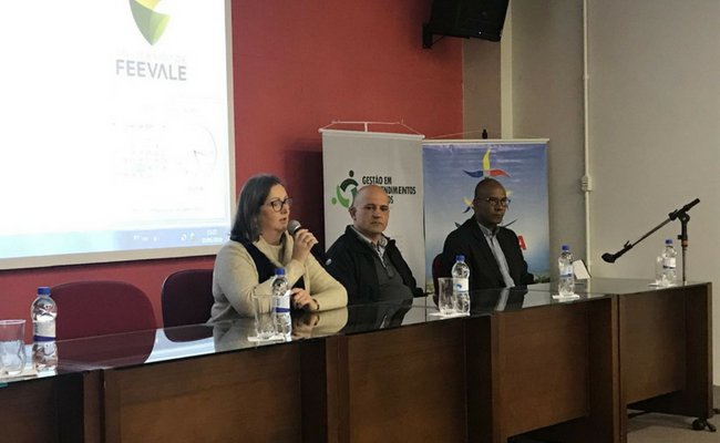 Dois homens e uma mulher sentados em um palco