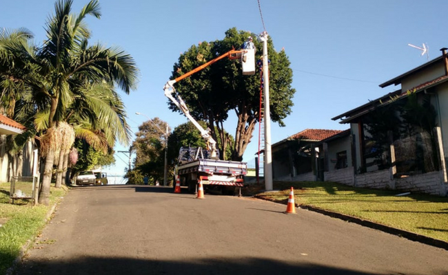 Um caminhão parado ao lado de um poste trocando uma lâmpada