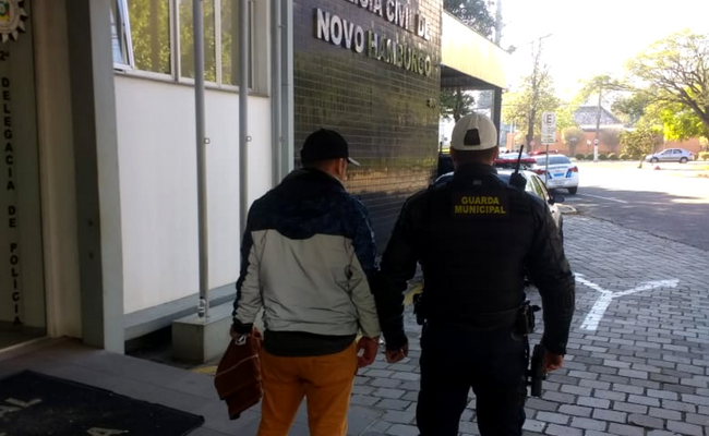 Guarda Municipal de costas com o preso também de costas