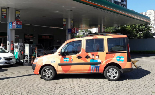Carro adesivado do Procon parado em frente a um posto