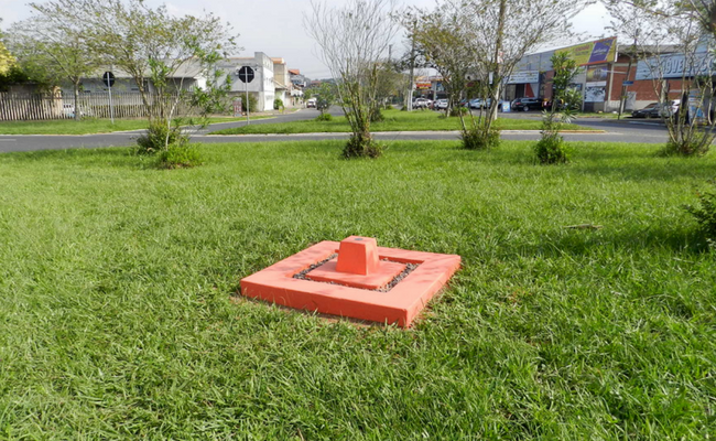Área de grama verde com um retângulo de concreto em laranja no centro