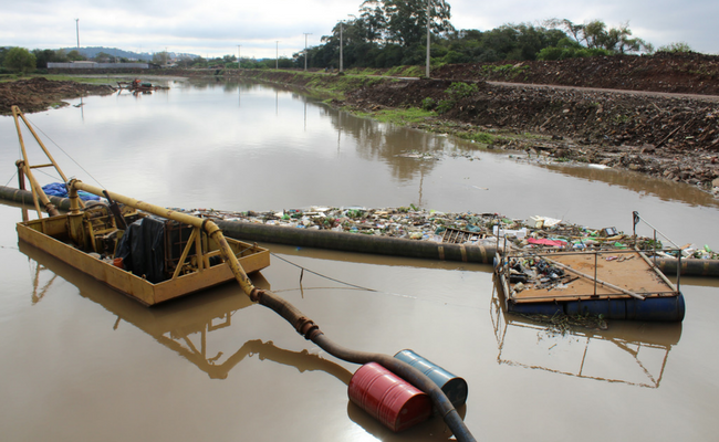 Rio e uma bóia de contenção cheia de lixo