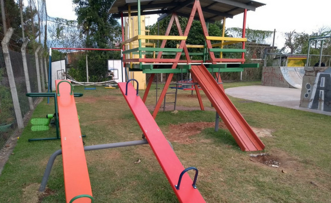 Duas gangorras e uma casinha de madeira ao fundo