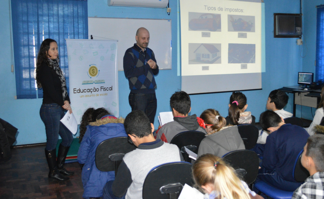 Professor em pé e alunos sentandos em uma sala de aula