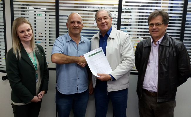 Udo Sarlet (o segundo na foto) em aperto de mão simbólico com o vice-presidente da Unimed Vale do Sinos, Ronaldo Scherer, que segura a Licença Prévia, junto à gerente da cooperativa Julia Habigzang e o consultor Rui Back