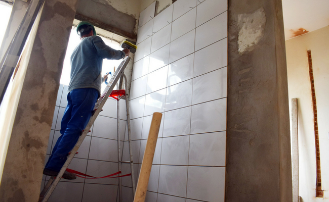 Homem em uma escada colocando azulejo