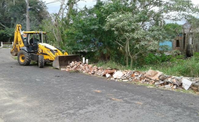 Máquina recolhendo materias de obras depositados em uma das ruas