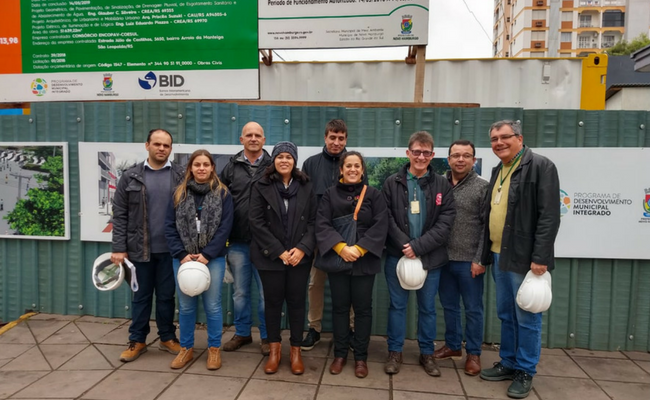 Equipes do BID e da Prefeitura parados com capacetes nas mãos