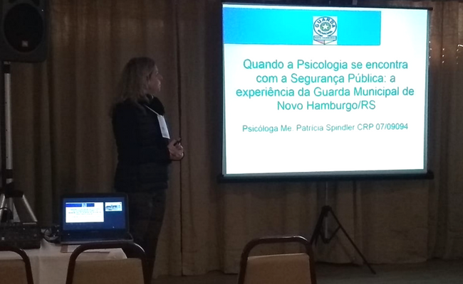 Psicólaga em pé e projeção da apresentaçã na parede