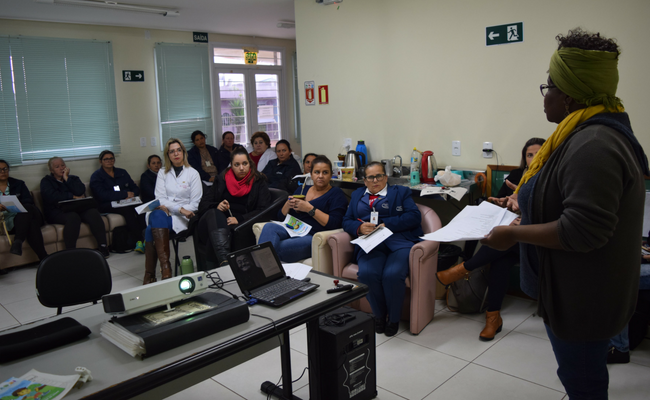 Cler em pé e profissionais sentados no entorno