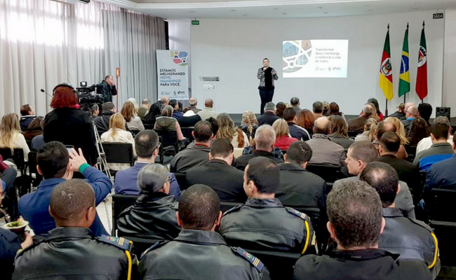 Prefeita em pé ao microfone e plateia sentada