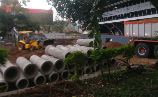 Canos de esgoto empilhados e ao lado um caminhão