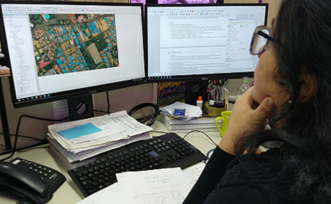 Mulher sentada olhando dois monitores de computador