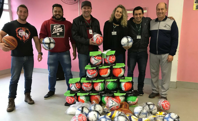 Seis pessoas em pé com bolas na mão. Conjunto de bolas no chão.