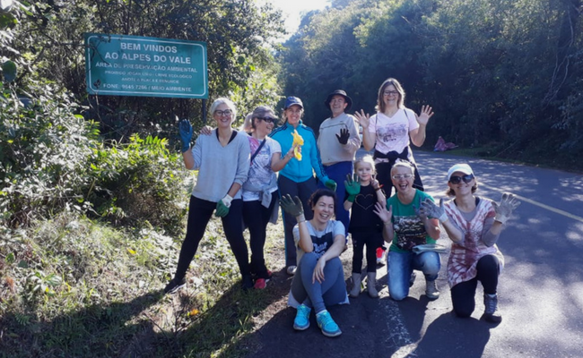 Em uma estrada, cinco pessoas estão em pé e quatro abaixadas paradas para tirar a foto