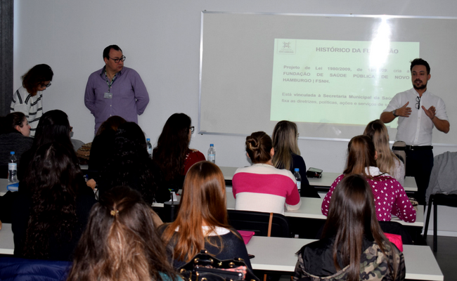 À direita, Rafaga em pé, com alunos sentados em cadeiras individuais de frente para ele