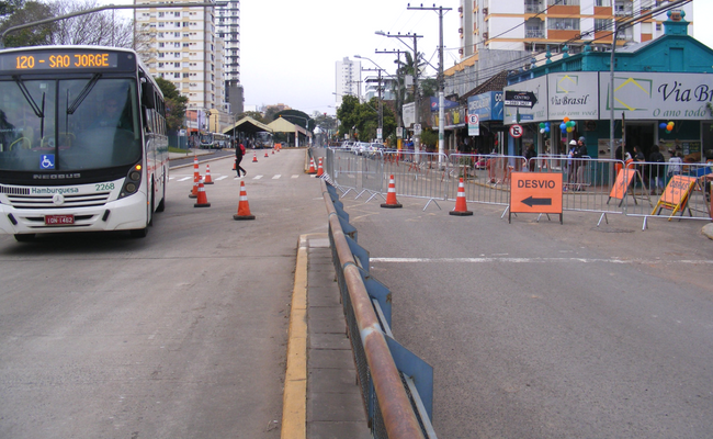 Cones laranjas indicam o local fechado e o desvio dos veículos em uma rua com duas pistas 