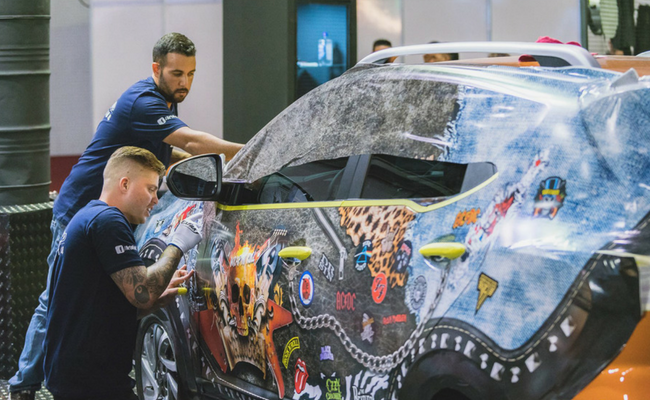 Uma carro parado com dois homens envelopando o veículo