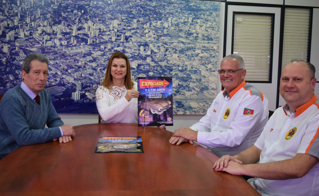 Sentados em uma mesa, a prefeita Fátima, Dr. Nei Sarmento e a direção do Veteran Car Club