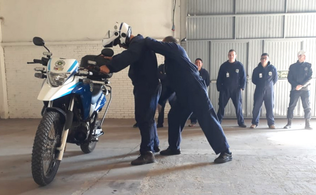 Escorado em uma moto, um guarda revista outro guarda