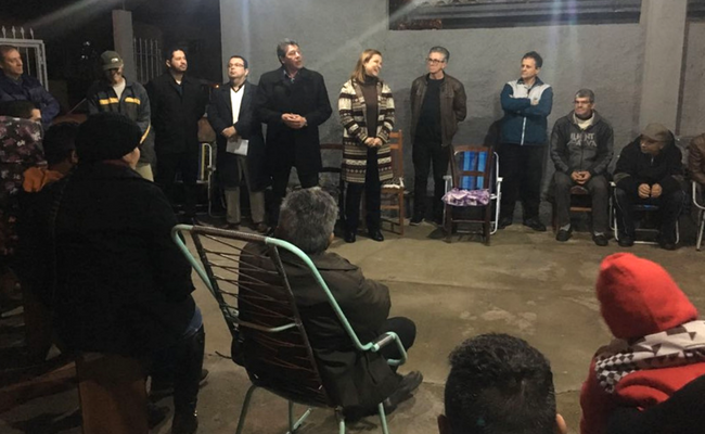 A prefeita em pé e os moradores sentando em círculo