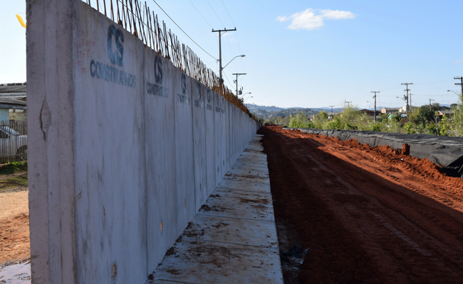 À esquerda muro de concreto e à direita a rua com terra