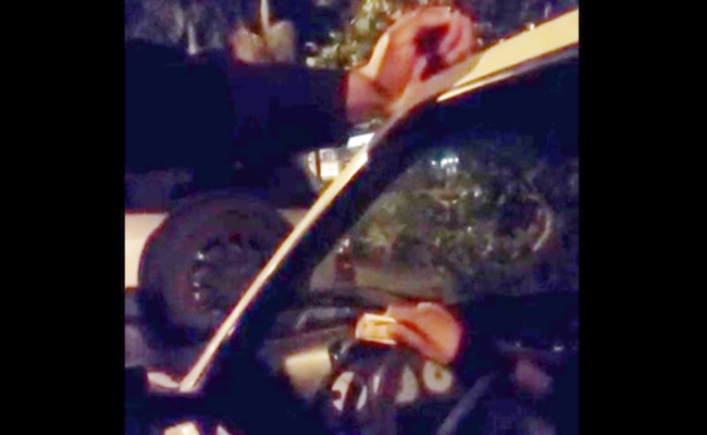 Dentro de um carro, o condutor está com dinheiro enrolado na mão