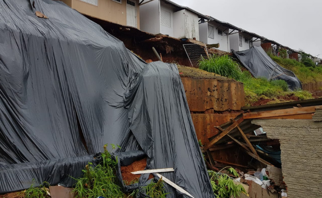 Em cima casas. Embaixo, um morro de terra que desmoronou no bairro boa saúde e atingiu uma casa