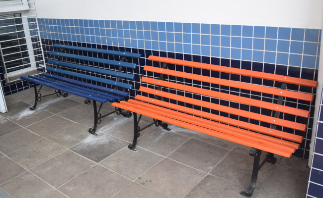 Dois bancos de madeira em tiras, um da cor laranja e outro azul, um ao lado do outro