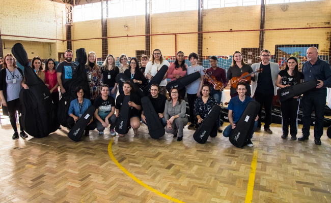 Professores, alunos e autoridades parados lado a lado com os instrumentos