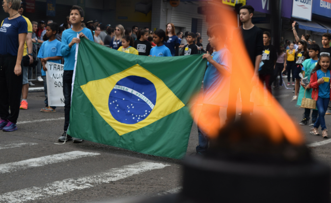 Ao fundo, a bandeira do Brasil. À frente, o fogo simbólico em uma pira
