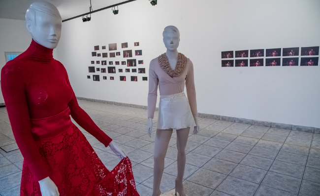 Dois bonecos em pé. Um vestido de branco e outro de vermelho, em uma sala branca