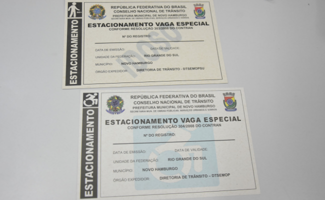 Em uma mesa, os cartões com uma faixa verde na lateral escrito estacionamento em branco. No centro, escrito em um cartão, estacionamento vaga especial e no outro estacionamento idoso