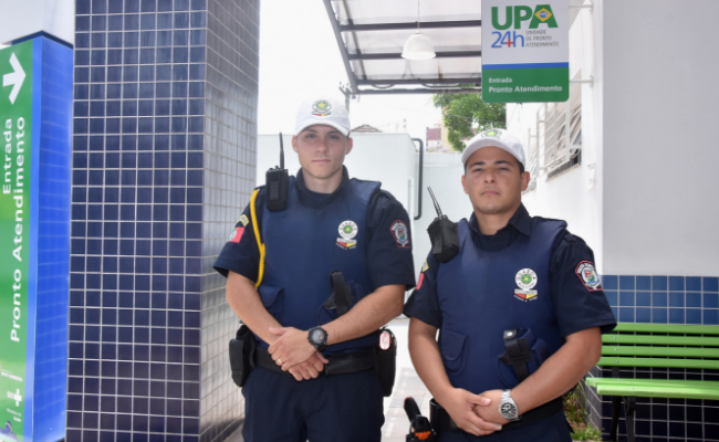 Dois guardas em pé e fardados em frente a UPA
