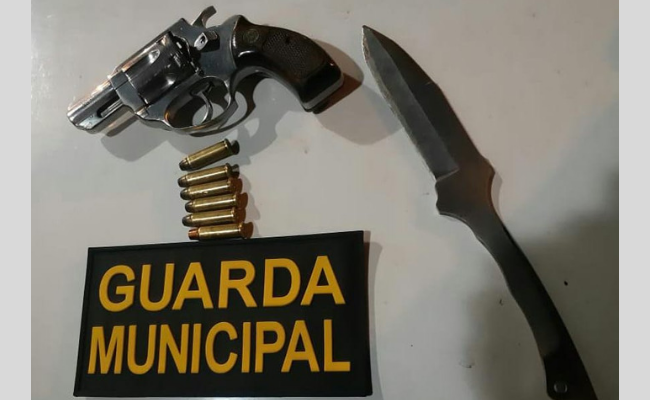 Uma arma, municção e o simbolo da Guarda Municipal