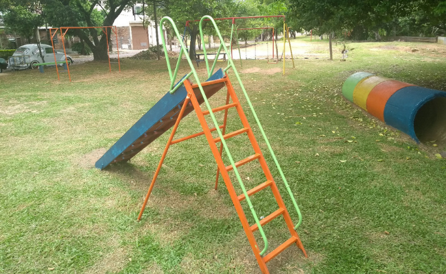 Imagem de uma praça com um escorregador na frente