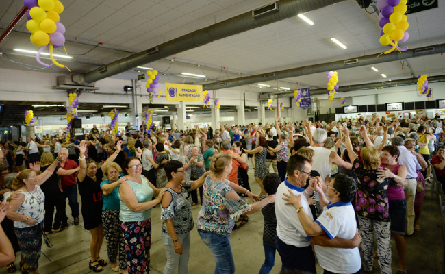Em grande salão, pessoas dançam