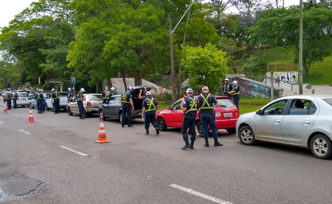 Carros parados em fila com guardas fazendo vistorias nos veículos