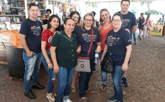 Oito pessoas em pé entre os estandes da Feira