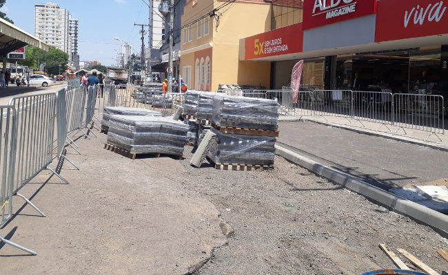 Do lado esquerdo, gradis. Ao centro, um monte de meios-fios empilhados. À direita, os meios-fios que já foram colocados na rua
