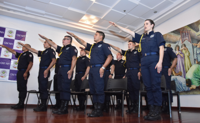 Doze pessoas em pé com o braço direito esticado para frente