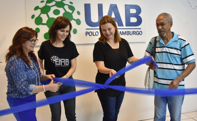 Secretária, Servidora, Prefeita e Servidor em pé, deslaçando um fita azul