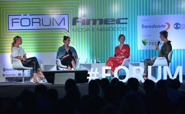 Em um palco, quatro pessoas sentadas