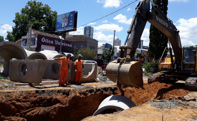Máquina colocando um cano em um buraco aberto na rua