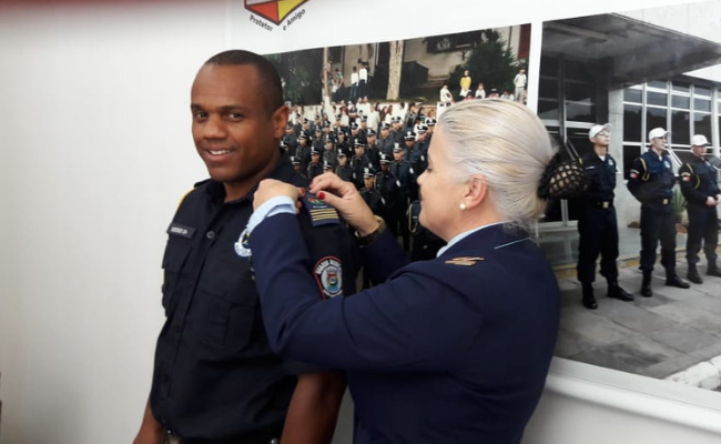 Ulisses em pé com a farda da Guarda Municipal com a então diretora Luíza também fardada