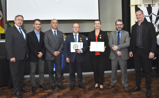 Sete pessoas em pé, com a prefeita segurando o diploma