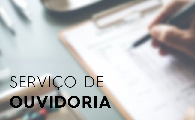 Imagem desfocada de uma mão escrevendo com um caneta em uma planilha. Escrito em preto serviço de Ouvidoria