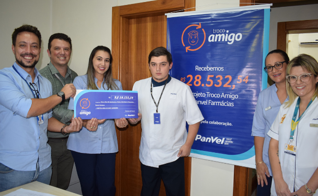 Seis pessoas em pé segurando um cheque
